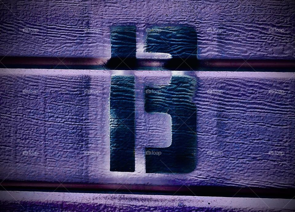 A stenciled “B” on a colored background with horizontal lines. It is dark color on a semi-light color.