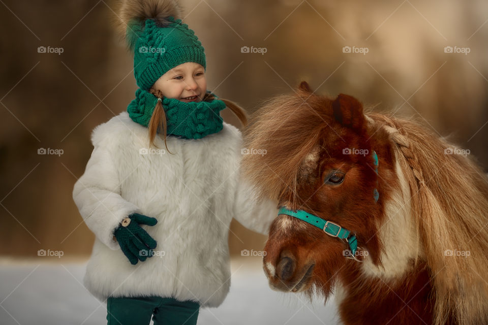 Little girl with pony at early spring day