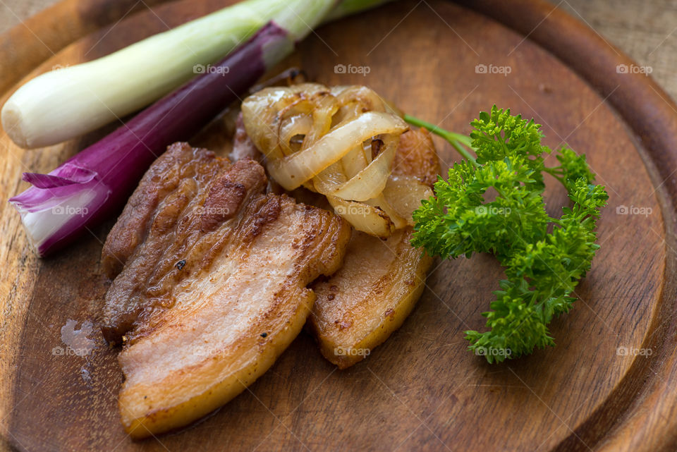 Cracklings with fried onion served with green onion and parsley on wooden cutting board