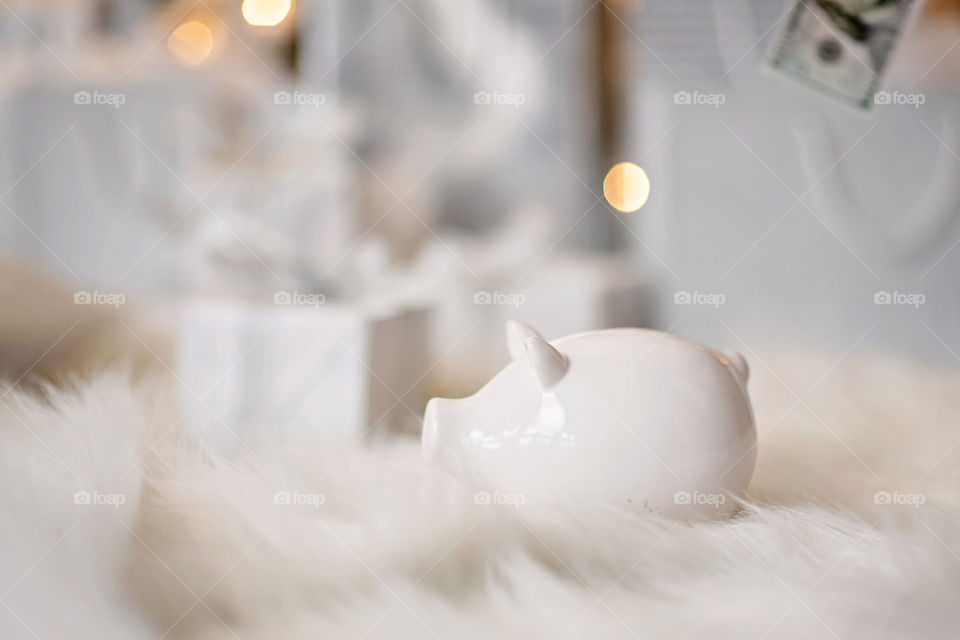 piggy bank with 100 dollars banknote in festive New Year atmosphere of scenery.  Magical bokeh with Christmas tree and bright lights.