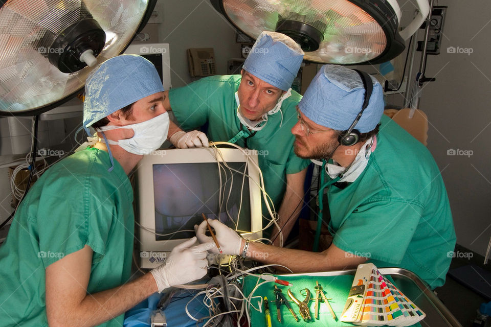 Three men operate on a computer in an operating room in the hospital