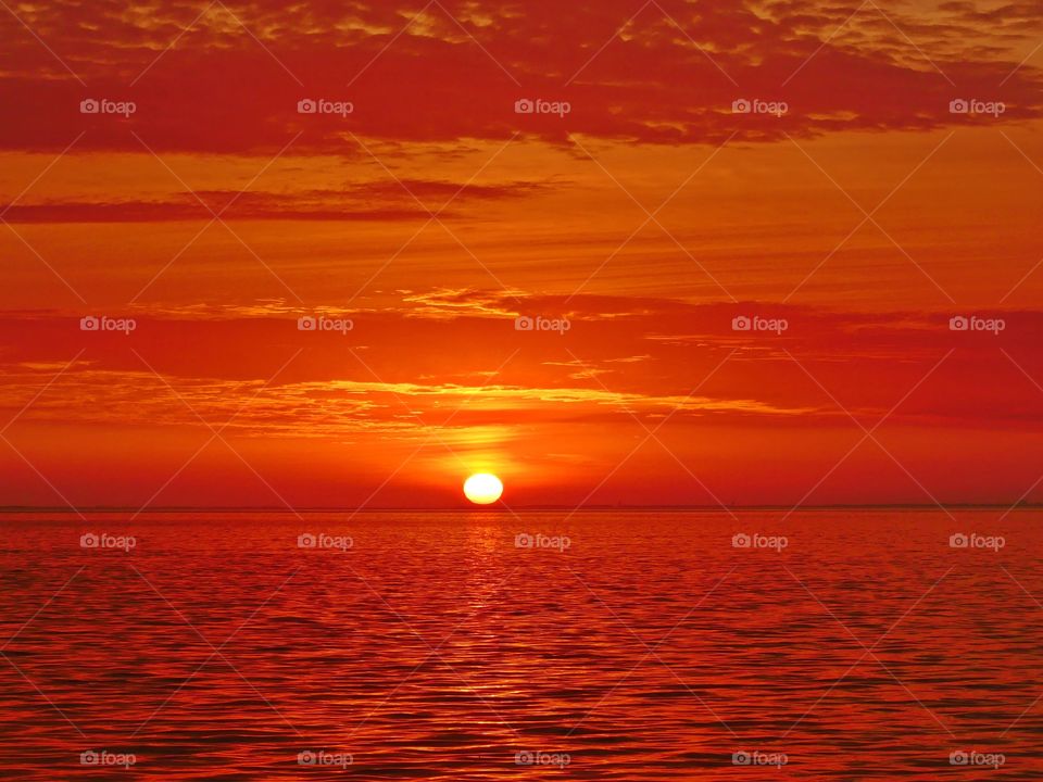 It was sunset. I watched with an unwavering gaze, as a fiery orange orb of light slowly sank beneath the horizon, and threads of light lingered in the sky, 
mingling with the clouds