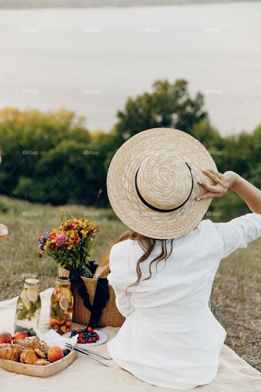Girl in white clothes holding hat on picnic time