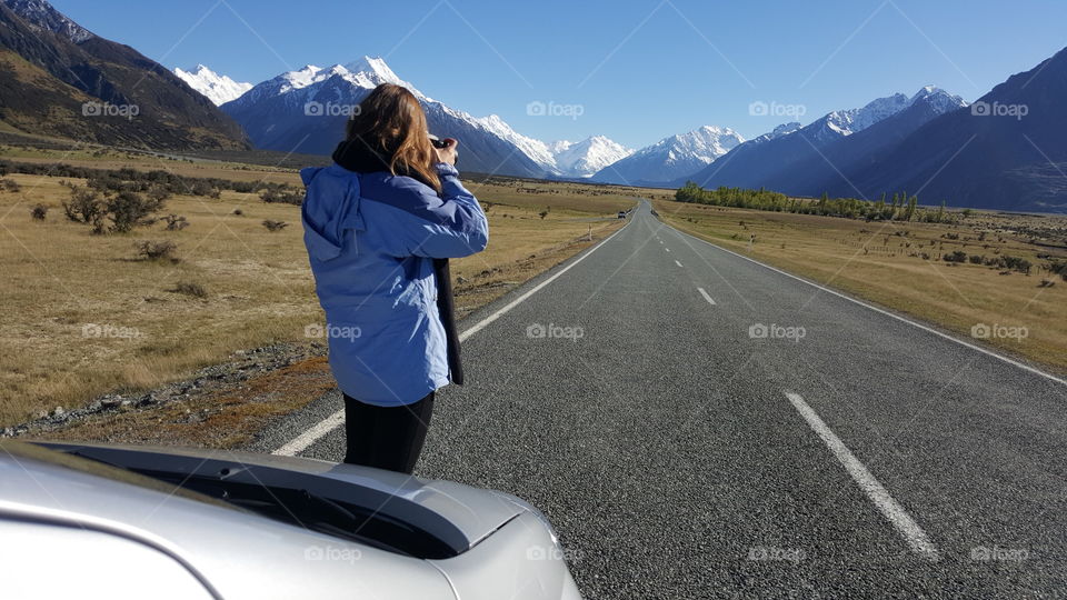 girl taking pictures of snowy mountains