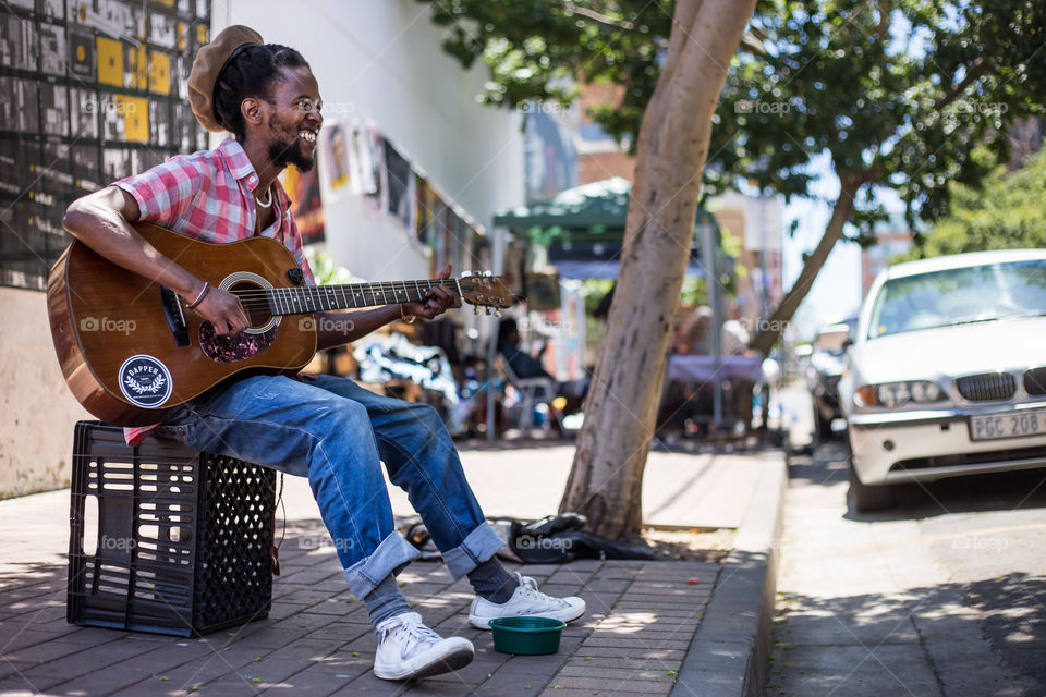 Man Busking on streets of Johannesburg.  Man singing and smiling in fashionable Maboneng District. 