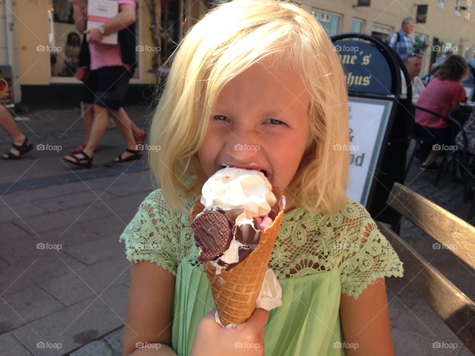 Portrait of cute blonde girl holding ice cream cone at street