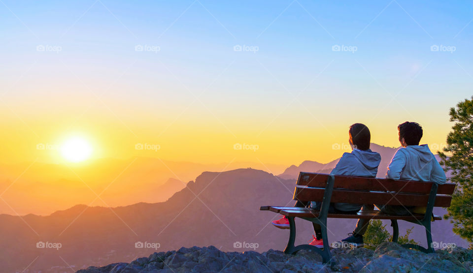 Romantic scene of a couple watching the sunset in mountain top