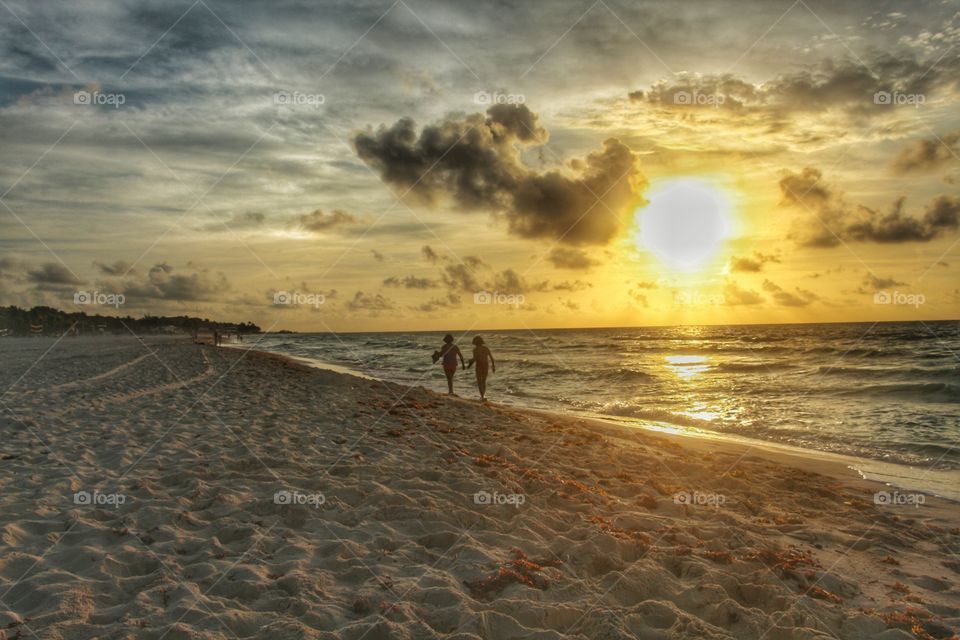 people walking in the beach at sunrise