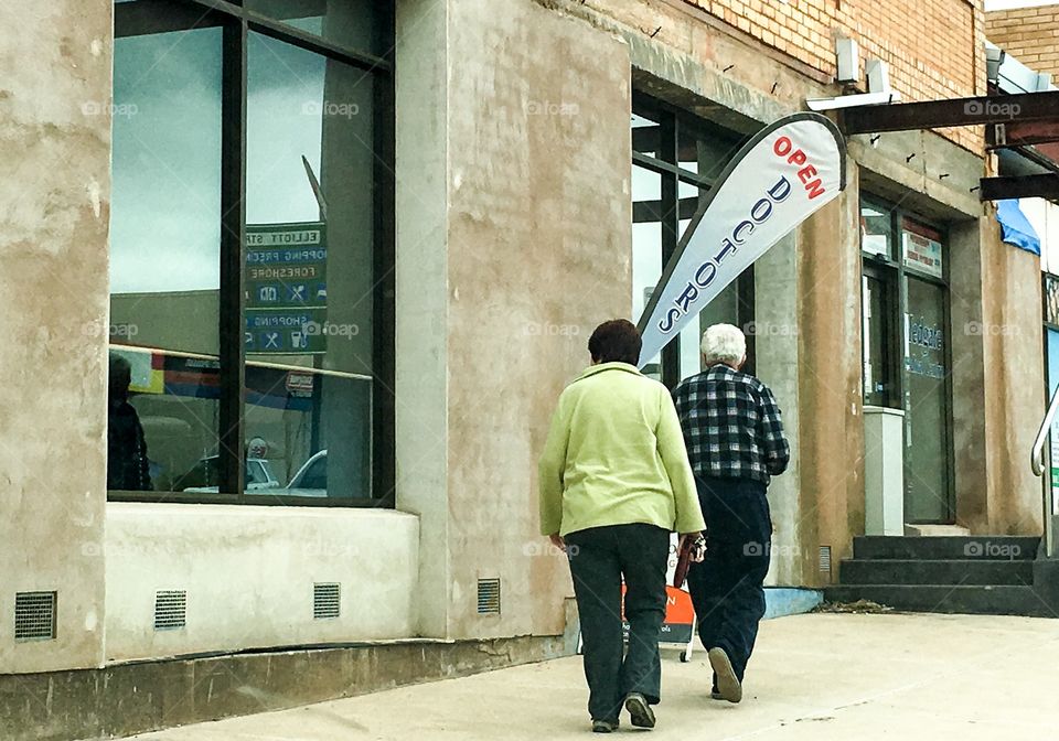 Couple on the street going into doctors office; kite style doctors sign