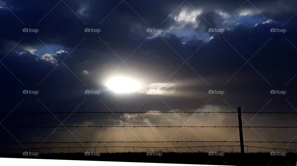 Clouds, sunset, sun rays and barbed wire