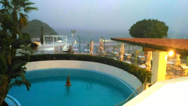 The round swimming pool with the garden of a hotel of the italian island of Ischia on an October stormy day