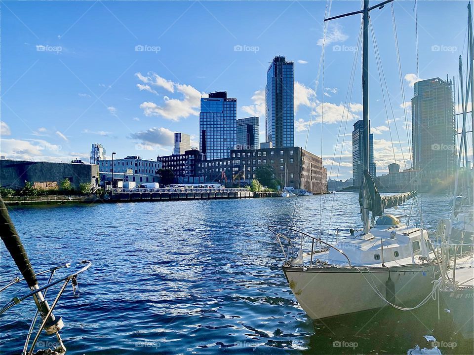 Seen in the golden hour of sunset the boats at “Newtown Creek” by the “Pulaski Bridge” in LIC look spectacular. The ocean sparkles in vibrant shades of blue topped with a silvery sheen and hints of rainbow refractions. 2023. Hypnotic Productions