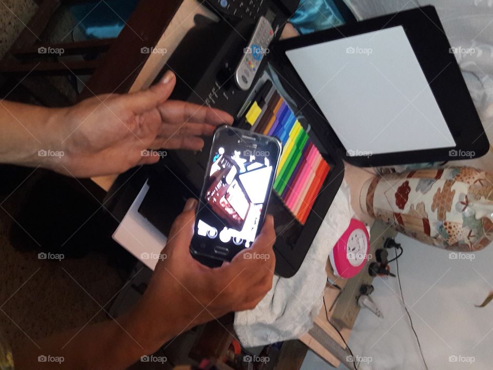 mobile phone clicking photo of printer scanner Xerox machine remote control paper wires home mess busy handheld landscape