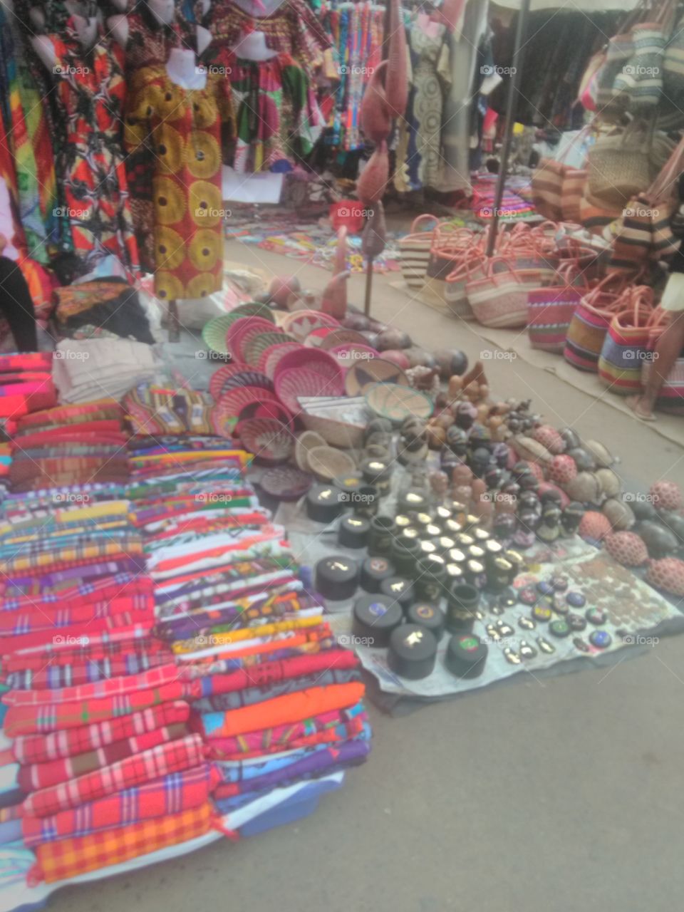 This photo shows African cultural items. They include  African baskets, African 'kitenge' attires, stone carvings, the Maasai community 'shukas' etc.