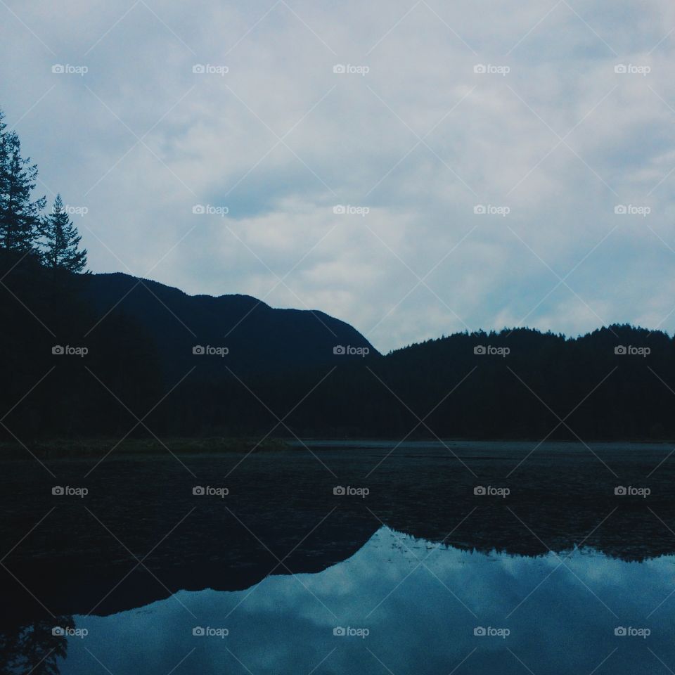 Silhouette of mountain reflecting on lake