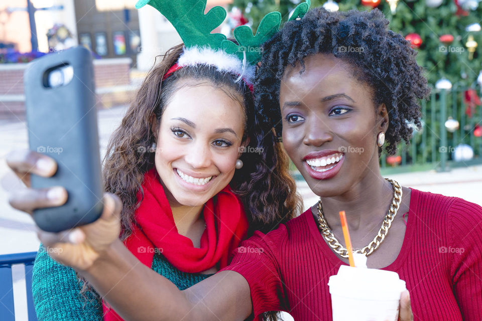 African woman taking selfie with asian friend