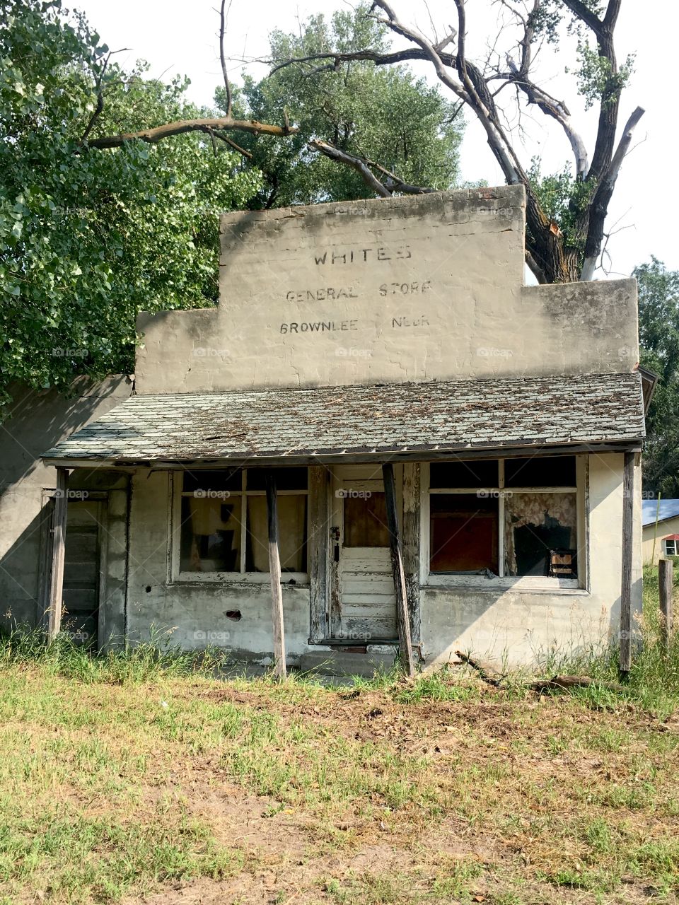 Old abandoned stucco building with a false front storefront and faded lettering