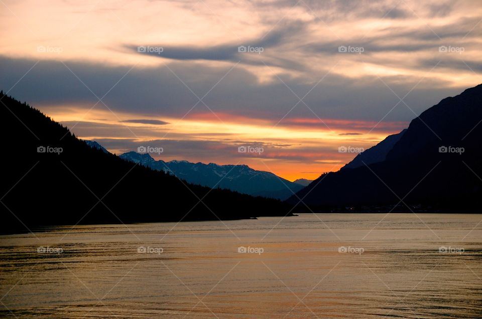 Scenic view of mountain by lake at sunset