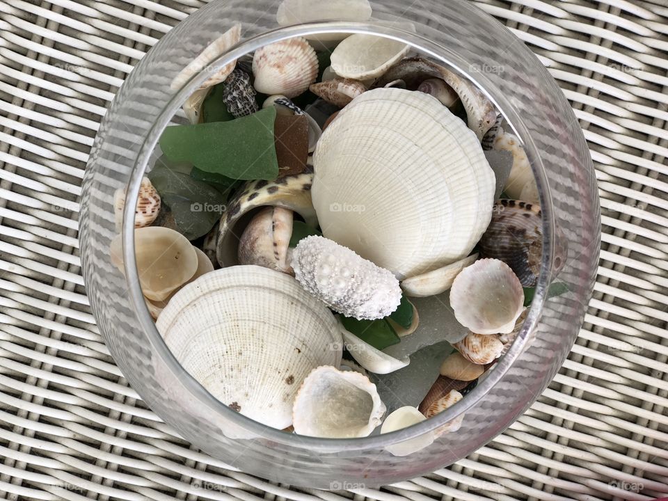 Shells and sea glass in bowl with wicker background 