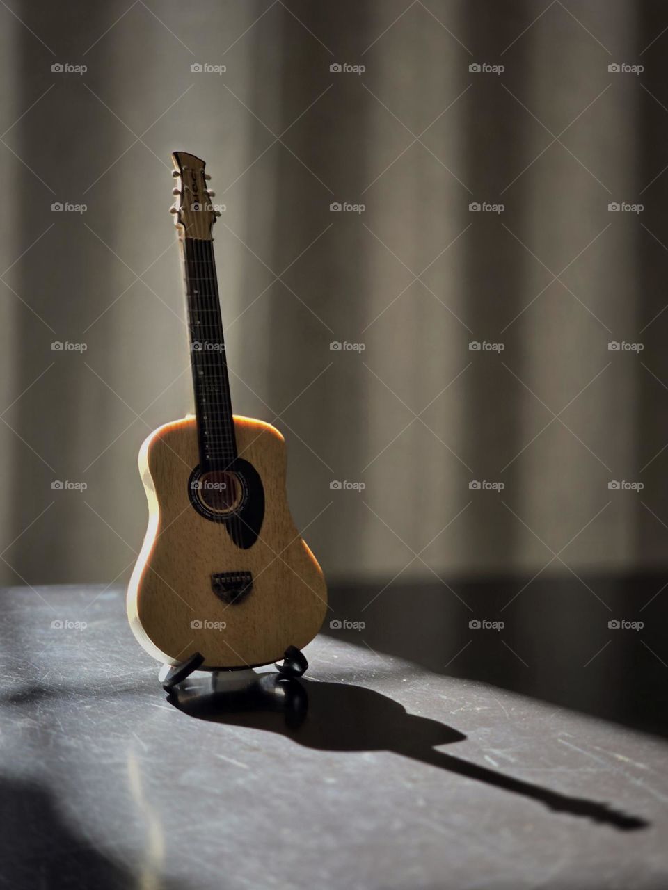 Small collection guitar placed on a table while receiving sunlight on it through the window.