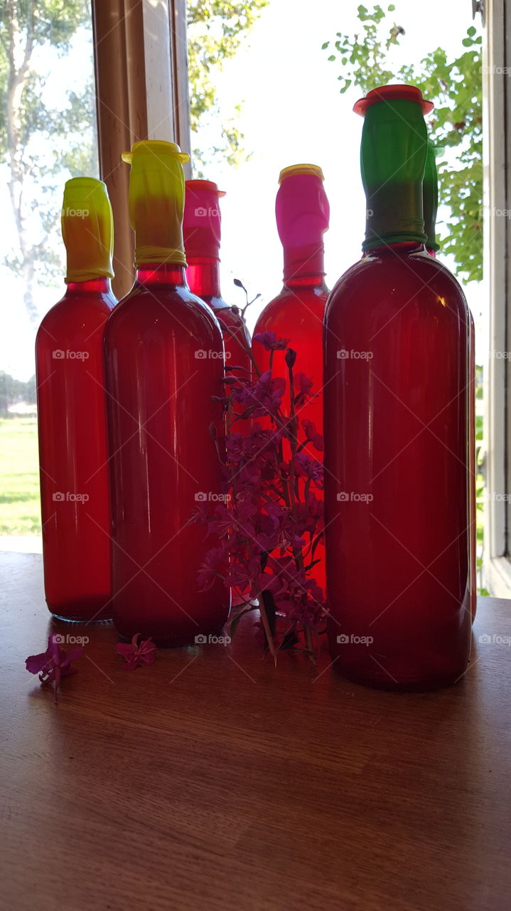 Red bottle with flower on table