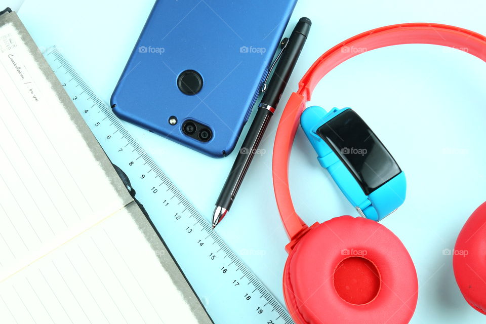 top view day to day gadgets and personal stuff. Smartphone, smartband, headphones, pen, notebook.