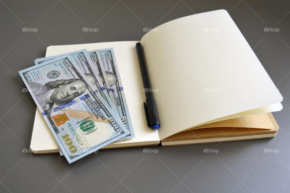 Dollars on the table with a notebook