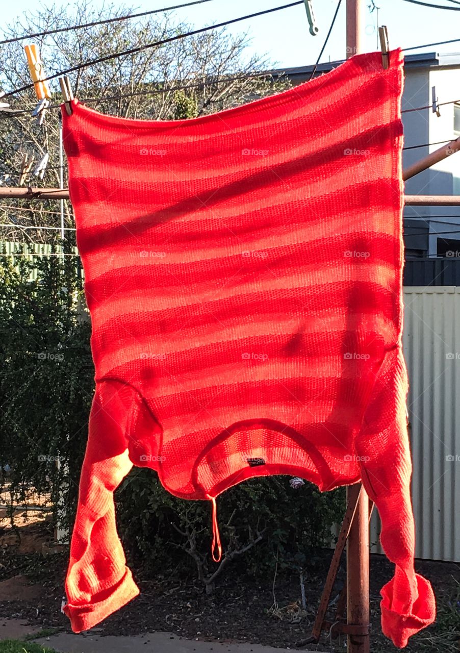 Orange coral melon colour sweater jumper hanging on a clothesline 