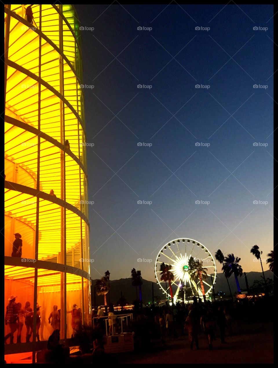 Yellow tower with Ferris wheel at sunset.