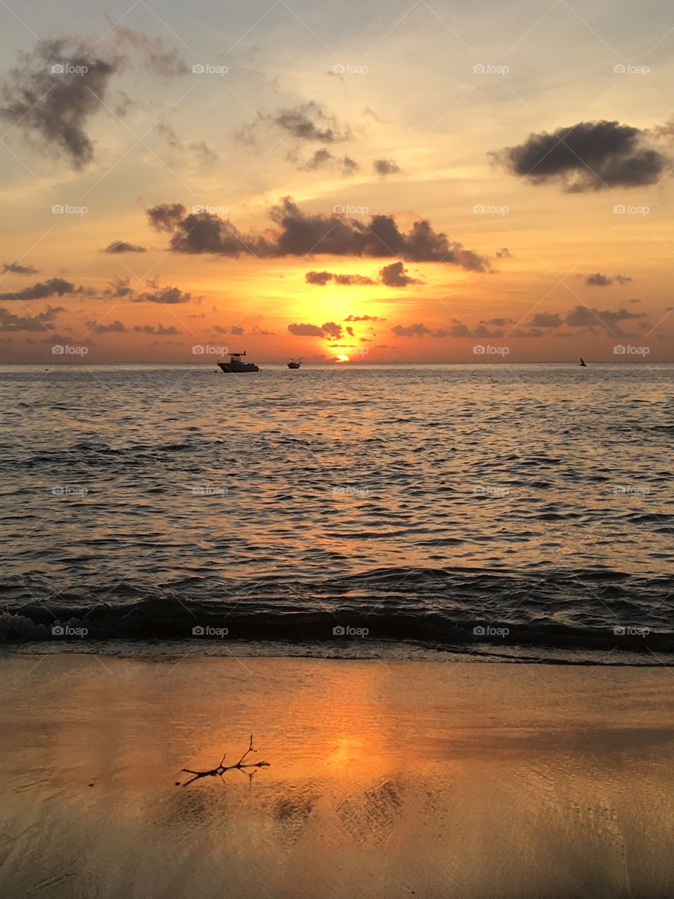 Silhouetted boat with sunset over sea