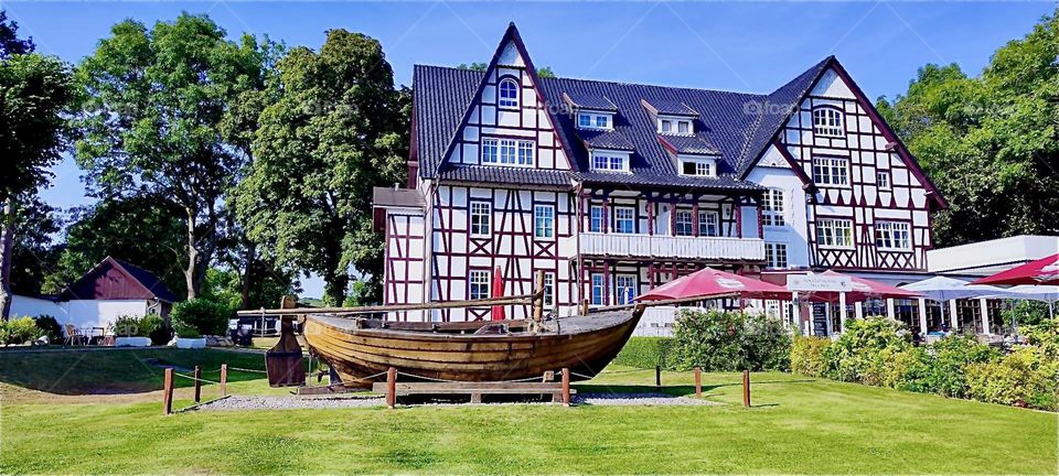 These beautiful old style half timbered houses can be found on the island “Hiddensee” in the “Baltic Sea” or “Ostsee” in “Western Pomerania”, Germany. The wooden handcrafted boat is currently on the hard for repairs. 2024. Hypnotic Productions