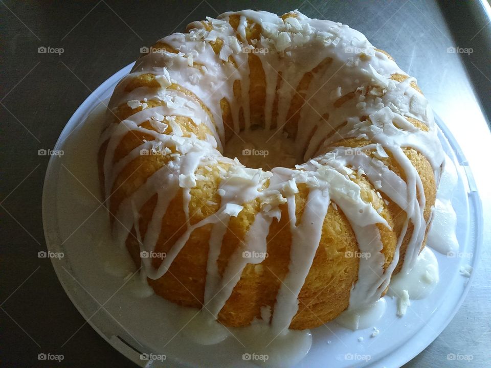 golden yellow pound cake with white dripped icing - home made in round mold