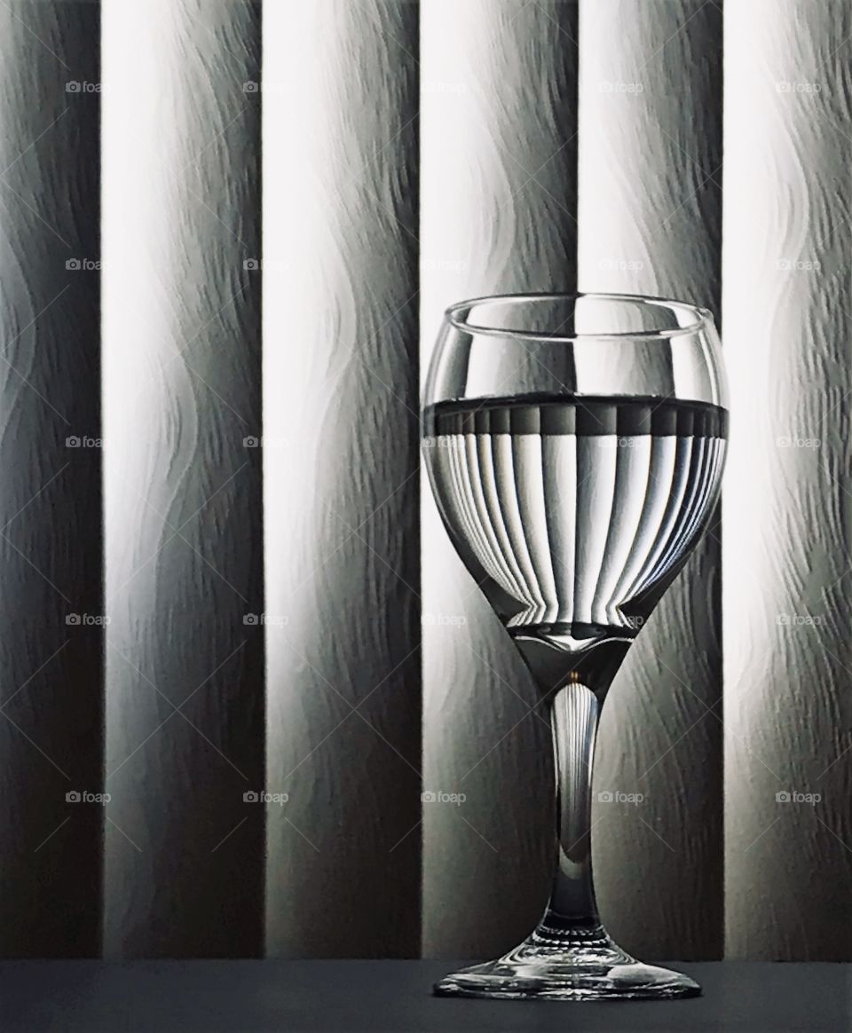 Black and White Goblet partially filled with blinds reflecting in the glass.