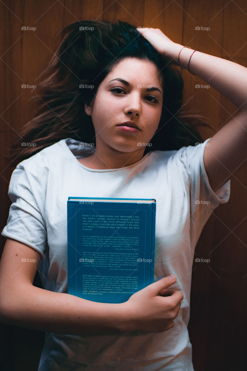 Girl lying on the floor at home with a book in her arms