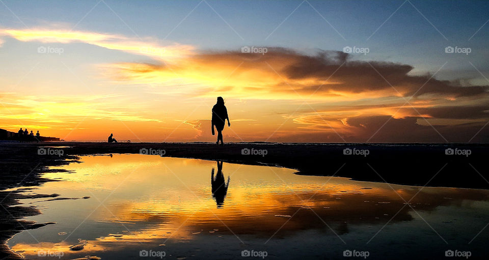 tourist walking on beach at sunrise.