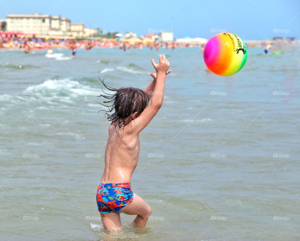 boy at sea plays ball