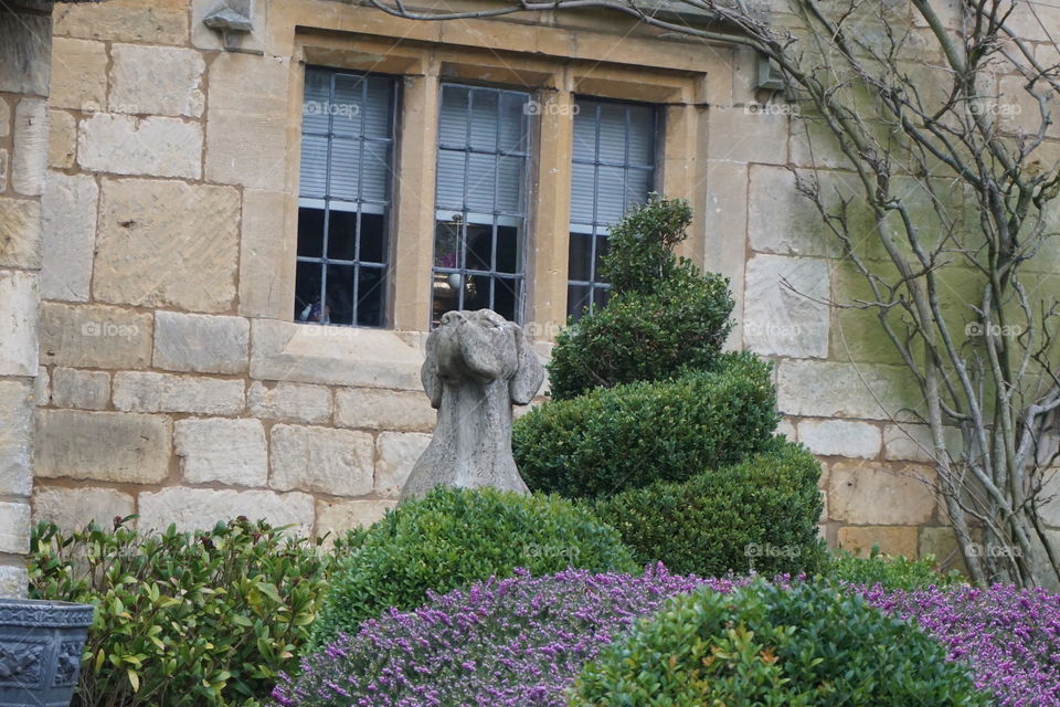 Stone statue outside a Cotswold cottage with s beautiful winter garden 