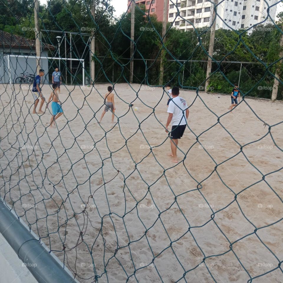 Children playing soccer in the sand in the city