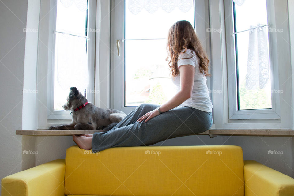 Woman and dog looking out window