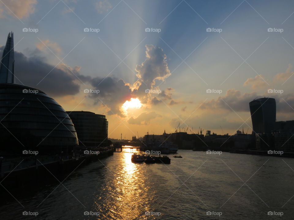 The beaming rays of the setting sun reflect on the Thames in London