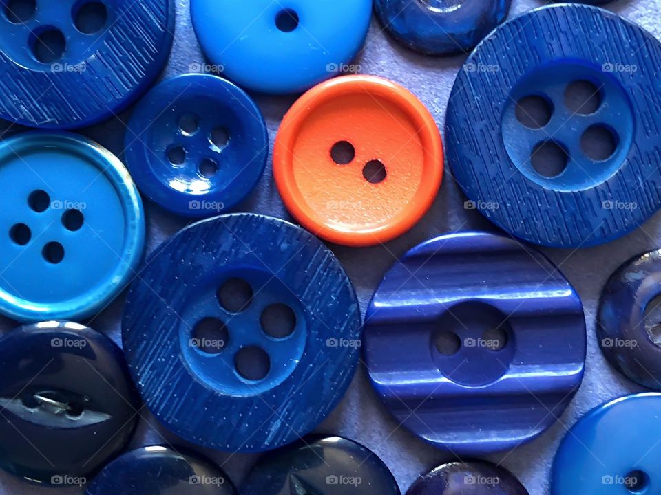 Several blue button and one orange button