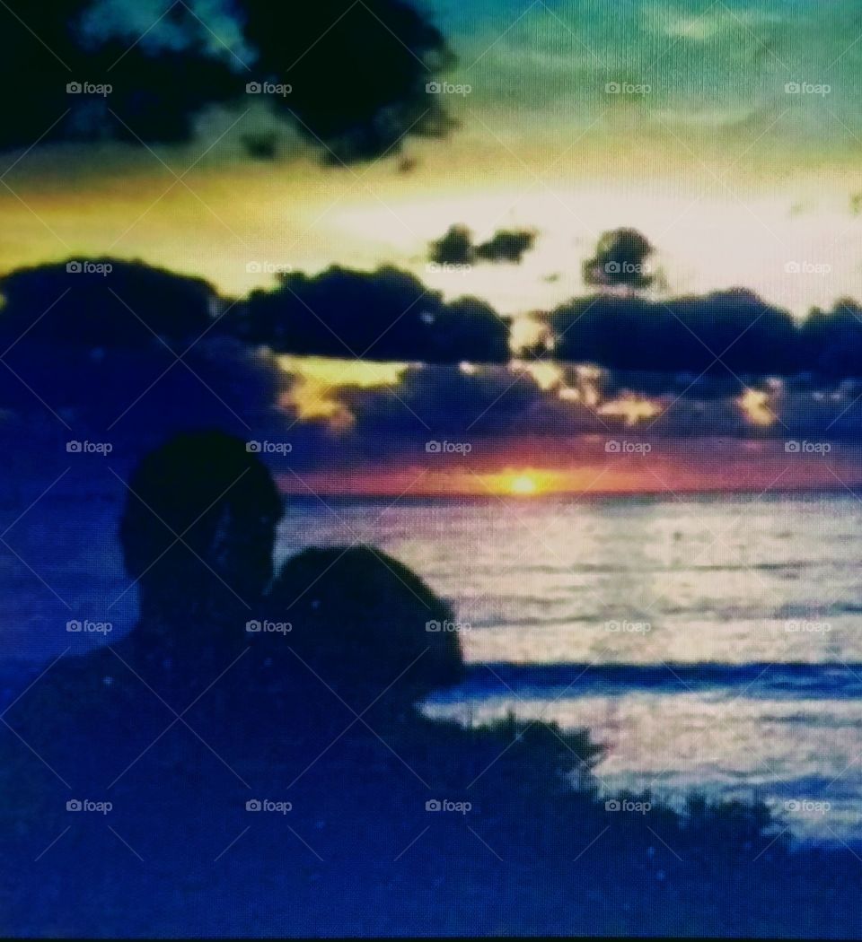 Sunsets & Sunrises! Here's a photo of people, a couple, in silhouette as they look at the sunset.