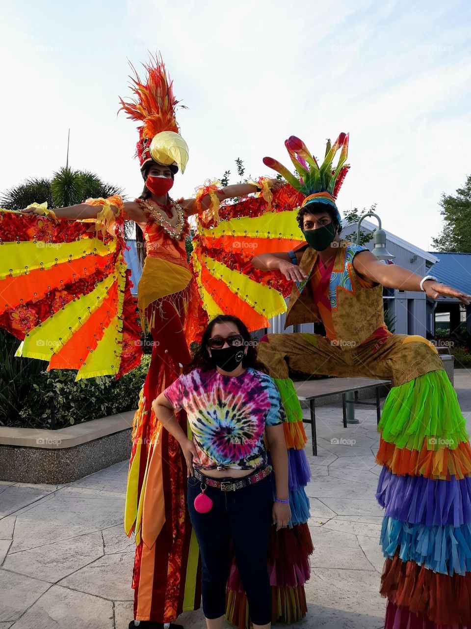 Colorful bird woman with companion greeting guest.