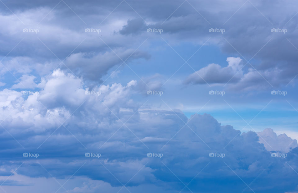 peaceful, dreamy, fluffy dark blue and white clouds floating in a lighter blue sky