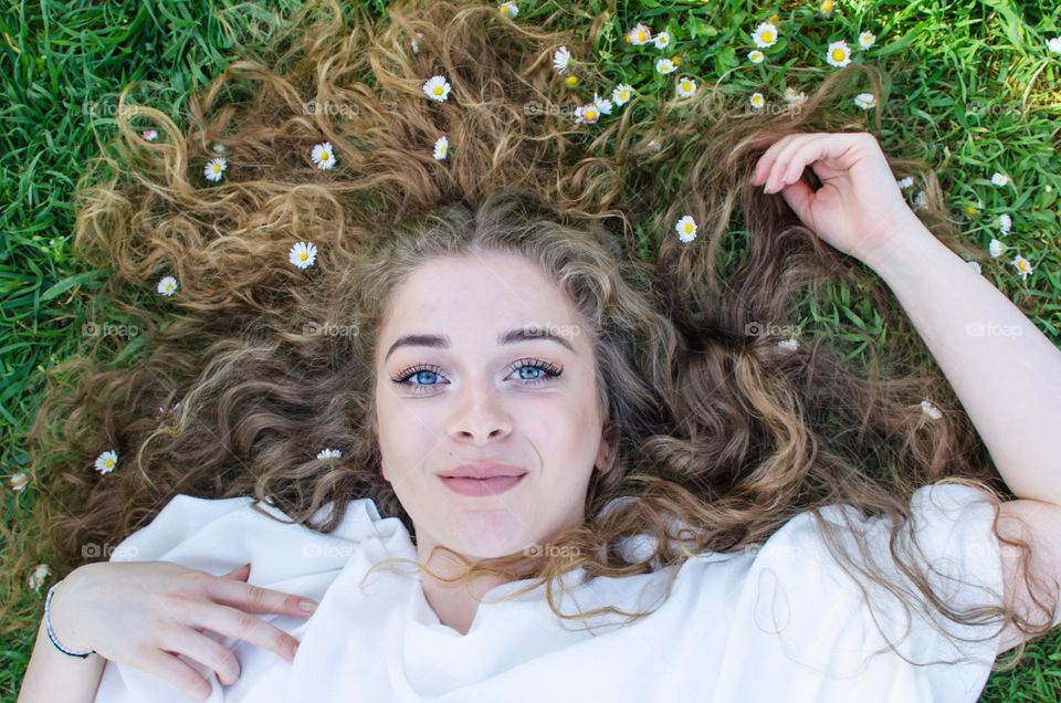 Woman with beautiful natural hair on background of daisies