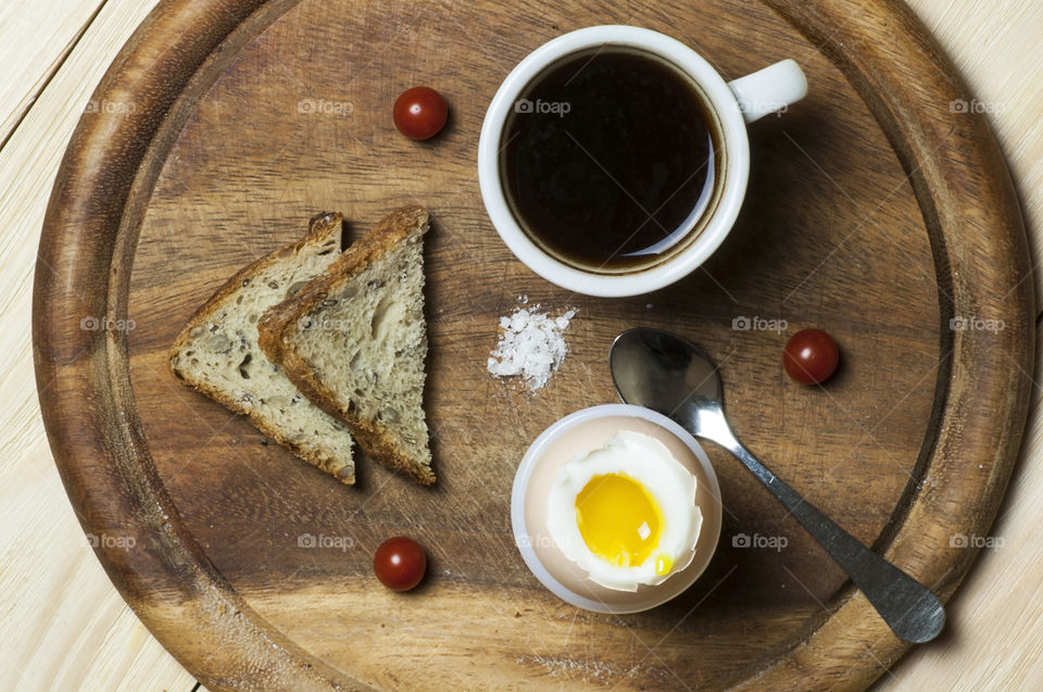 Light breakfast made of cup of coffee, boiled egg and toasts, view from above