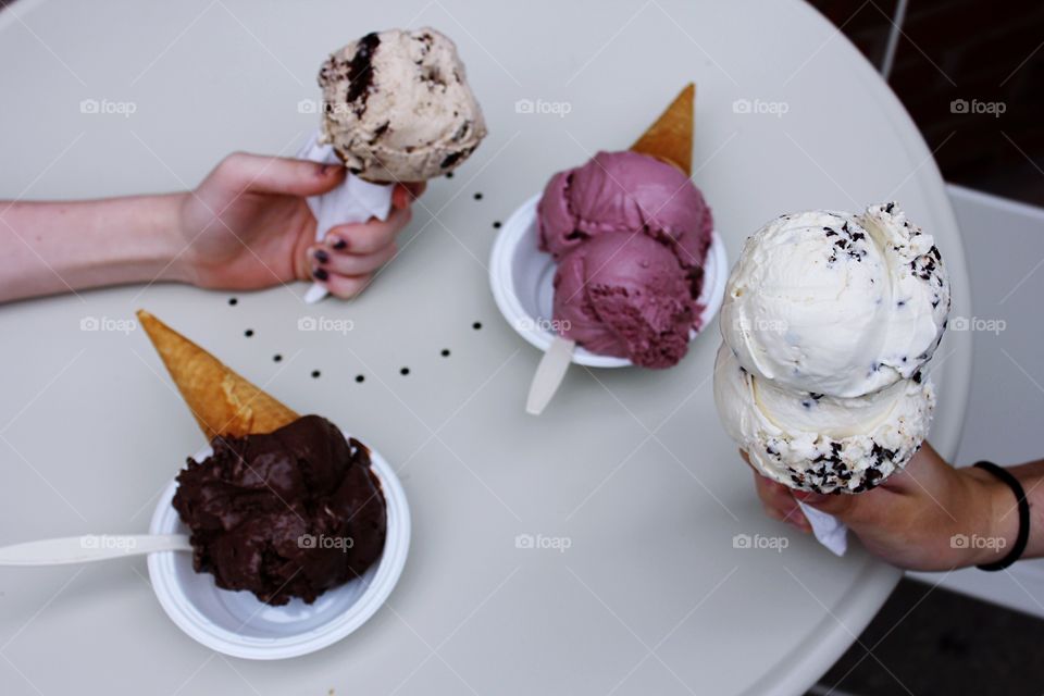 Persons holding ice cream on table