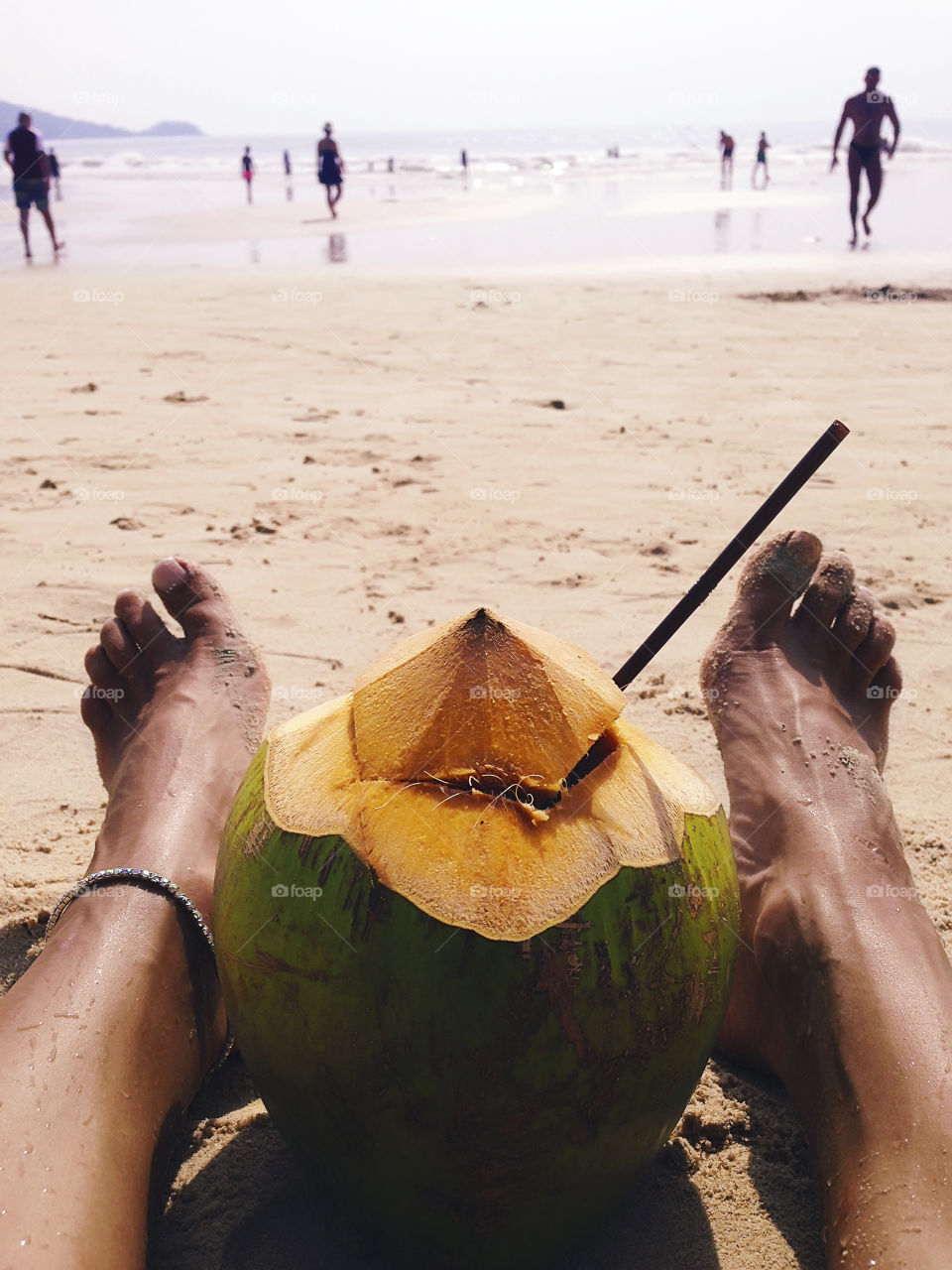 Enjoying the coconut cocktail at the tropical sandy beach during the summer tropical vacation 