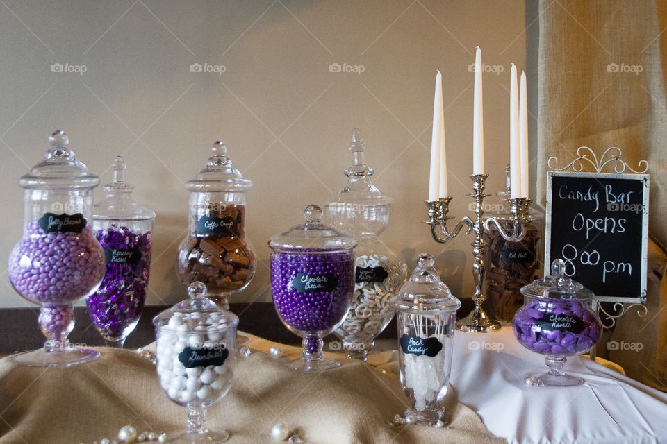 A sweets table at a wedding themed in purple, with candies in glass jars 