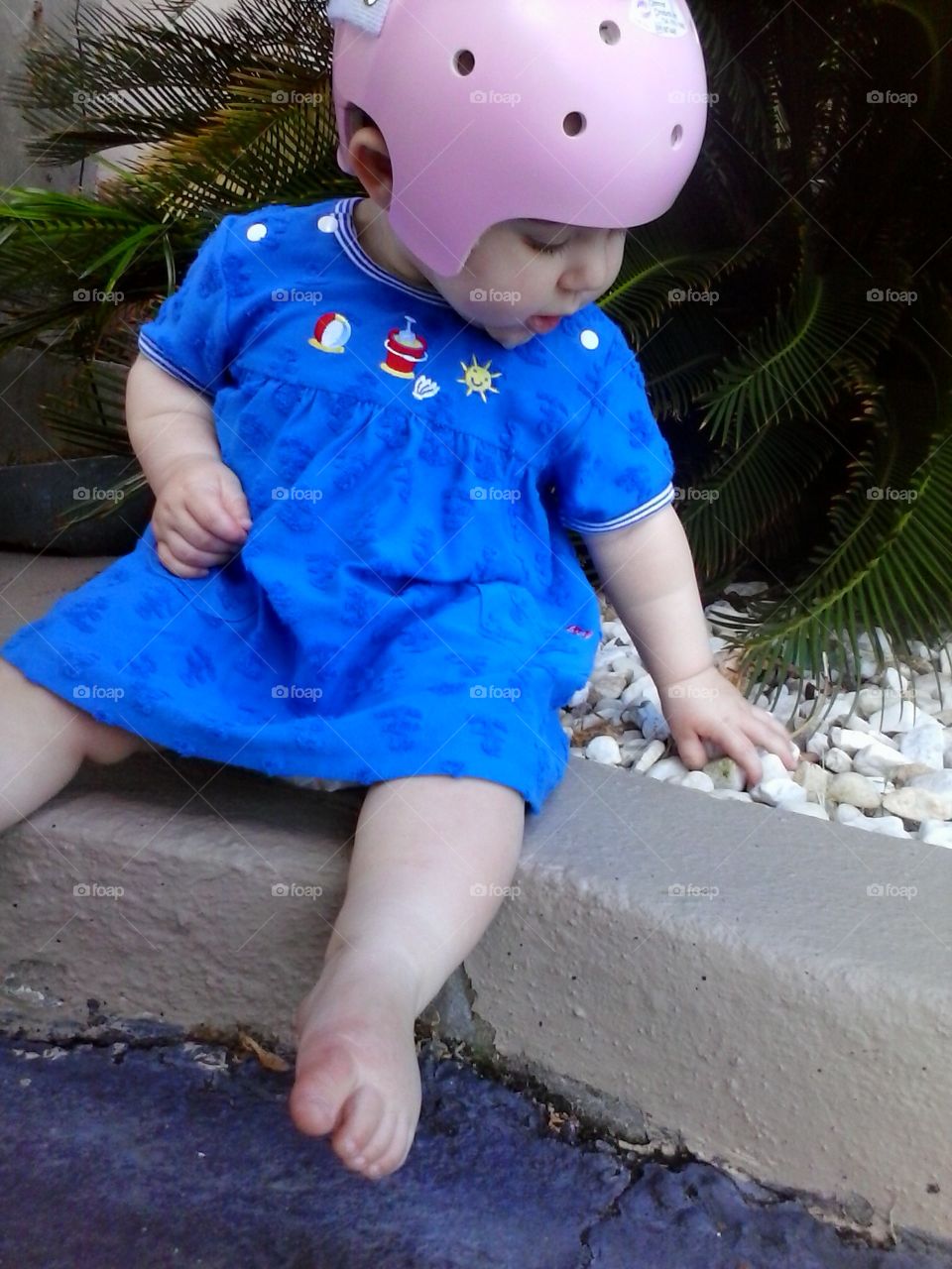 girl in a pink helmet. finding a cool spot to sit outside